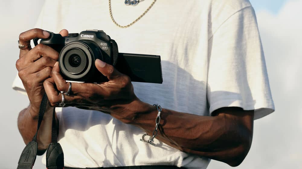Hombre sosteniendo una Canon EOS R7 Cámara sin espejo con objetivo 18-150 mm