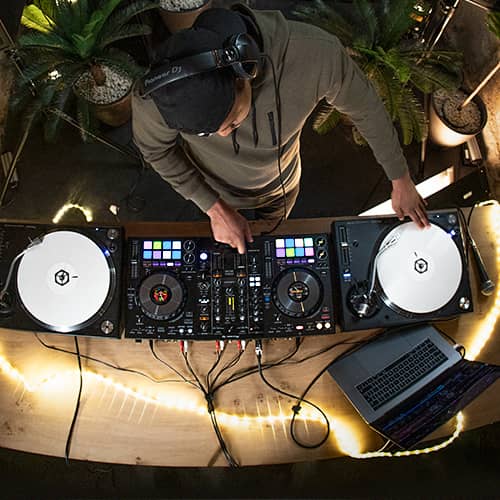 DJ manejando el Pioneer DJ DDJ-800 conectado a dos tornamesas vista superior