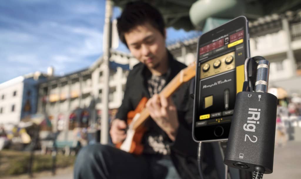 Hombre tocando una guitarra conectado al IK Multimedia iRig 2 con un móvil