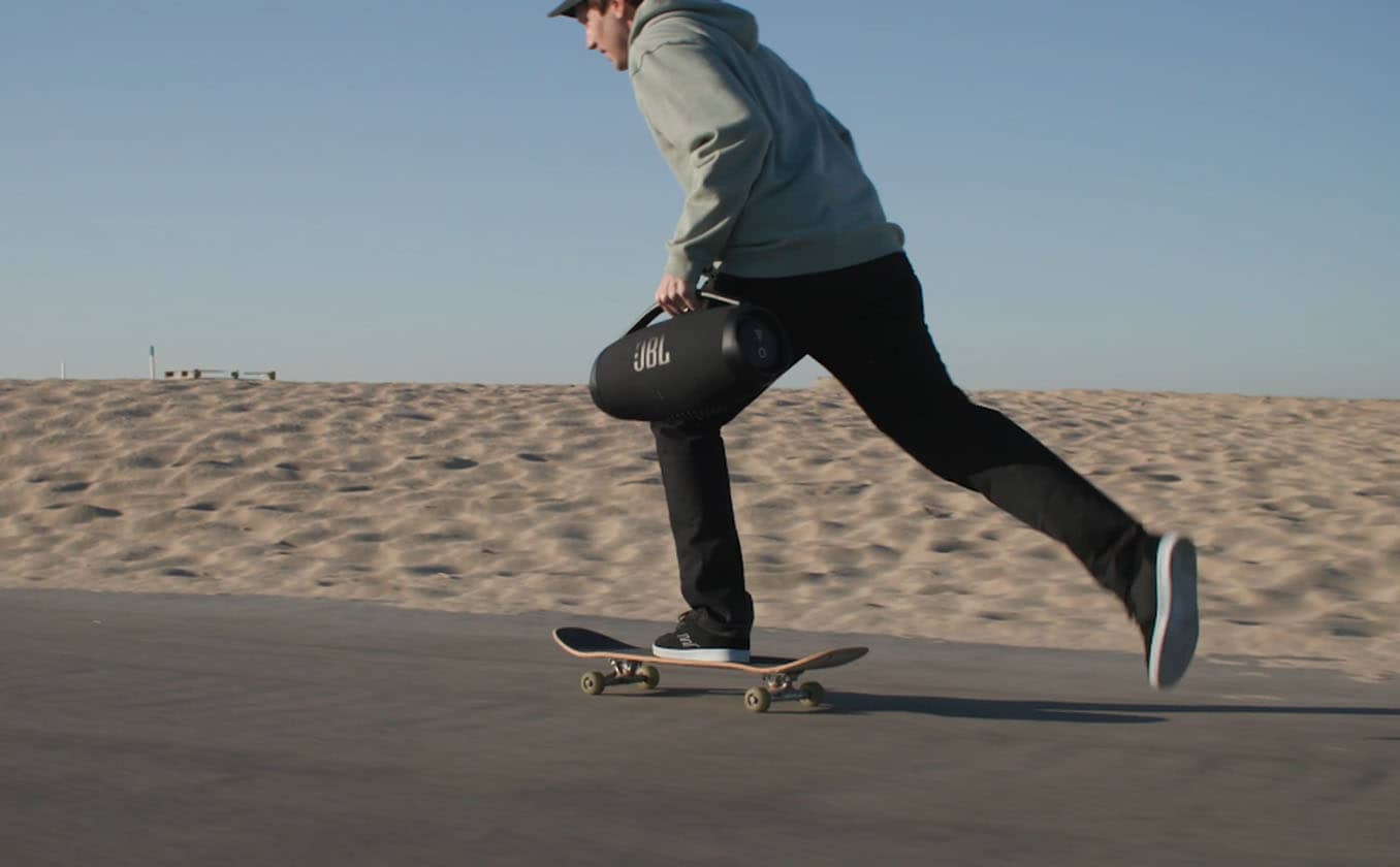 Hombre en patineta llevando un JBL Boombox 3 Altavoz Bluetooth Portátil (negro)