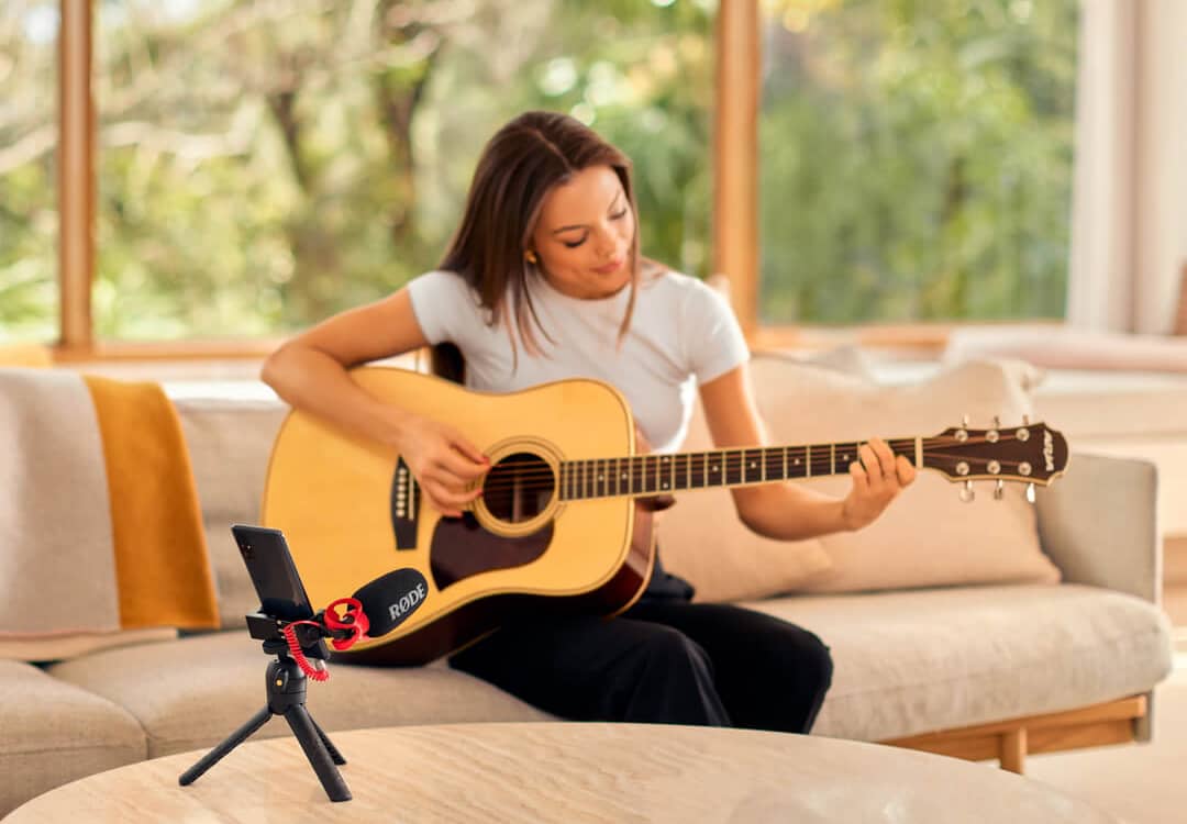 Mujer tocando guitarra usando el Videomicro II conectado a un smartphone